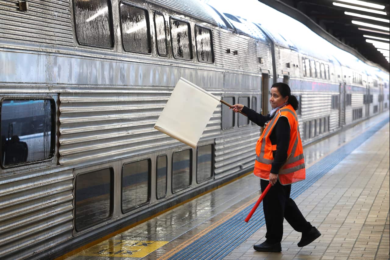 A rail worker signals a train driver at Central railway station on 17 October, 2022 in Sydney, Australia.