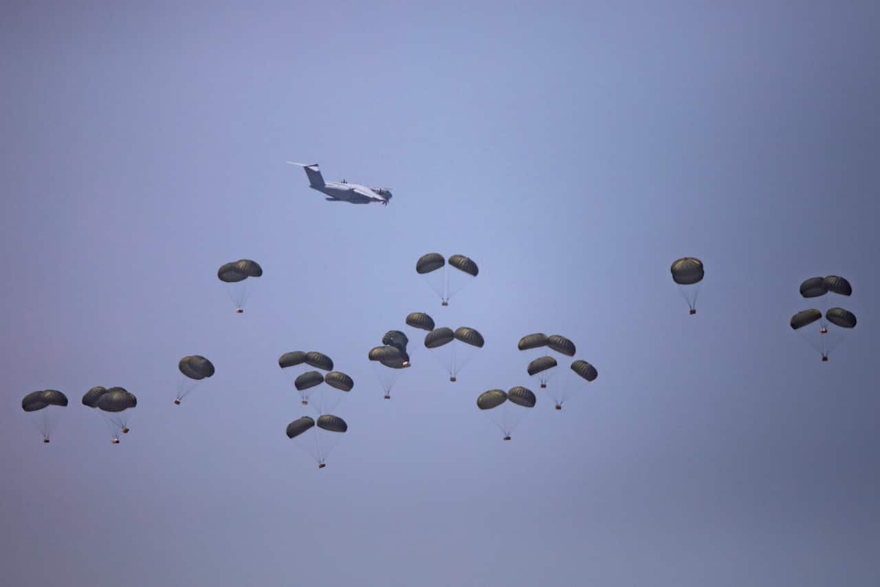 Dozens of parachutes falling from a plane.