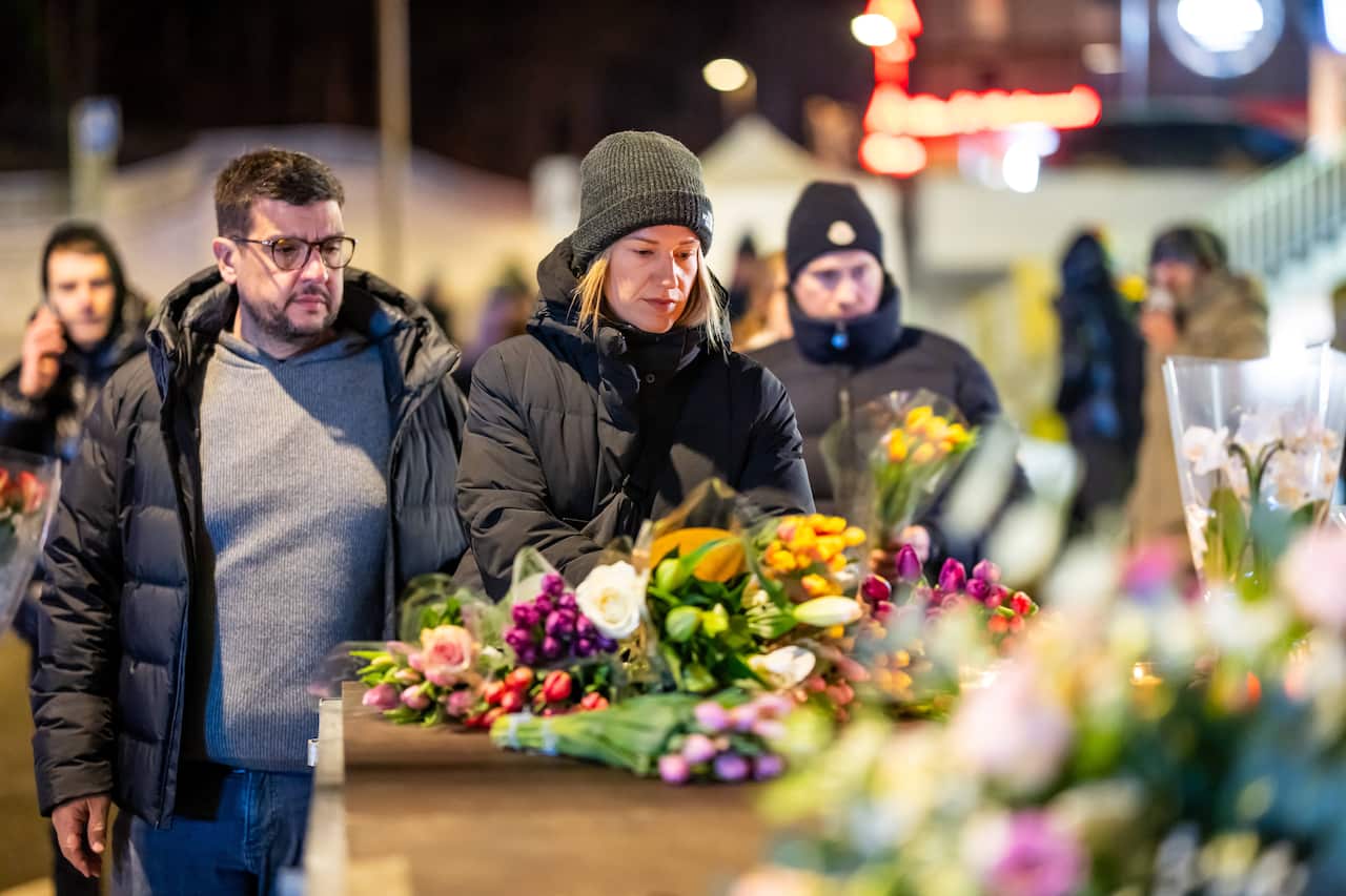 People lay flowers at an accident site.
