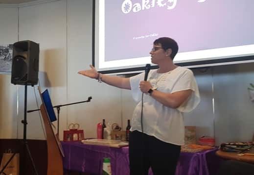 Tash speaking at a Parkinson’s event in front of a projector screen.