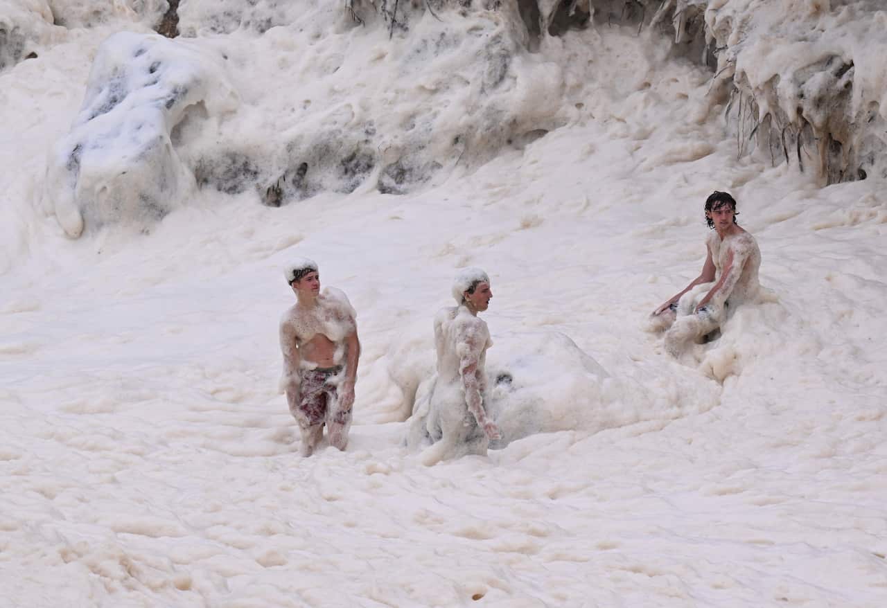 Three boys playing in sea-foam after a tropical cyclone.