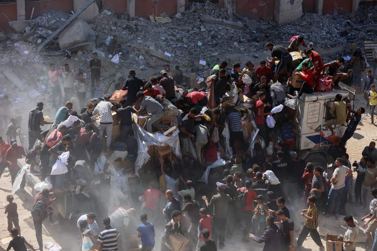 People rush to receive food parcels from aid trucks.