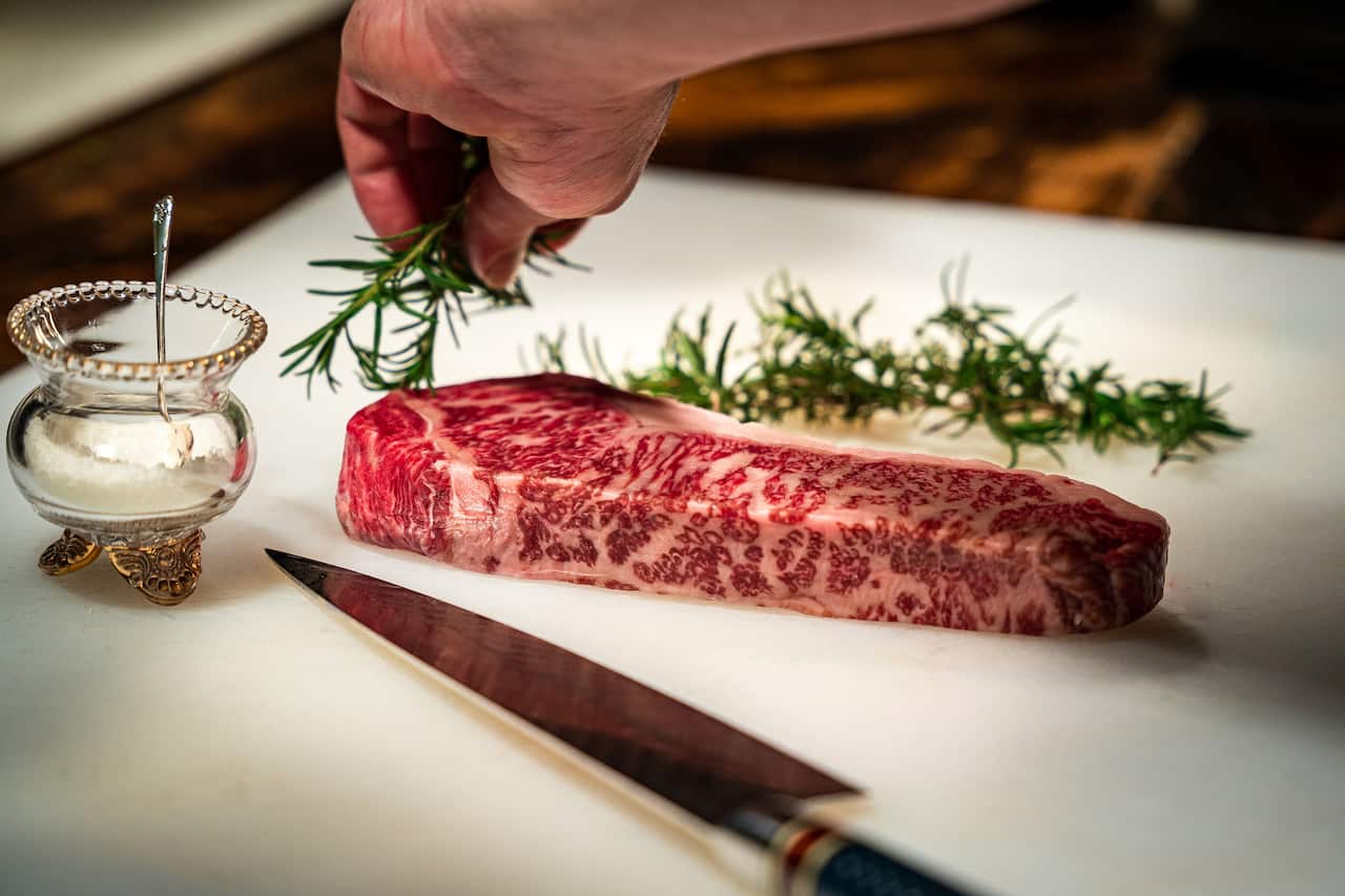Cropped hand cutting meat on table