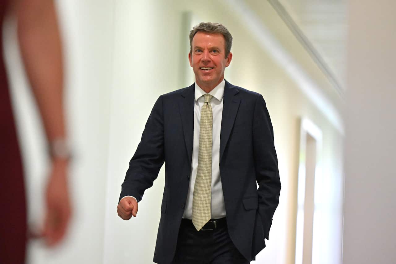 A middle-aged white man wearing a suit, walking down a corridor 