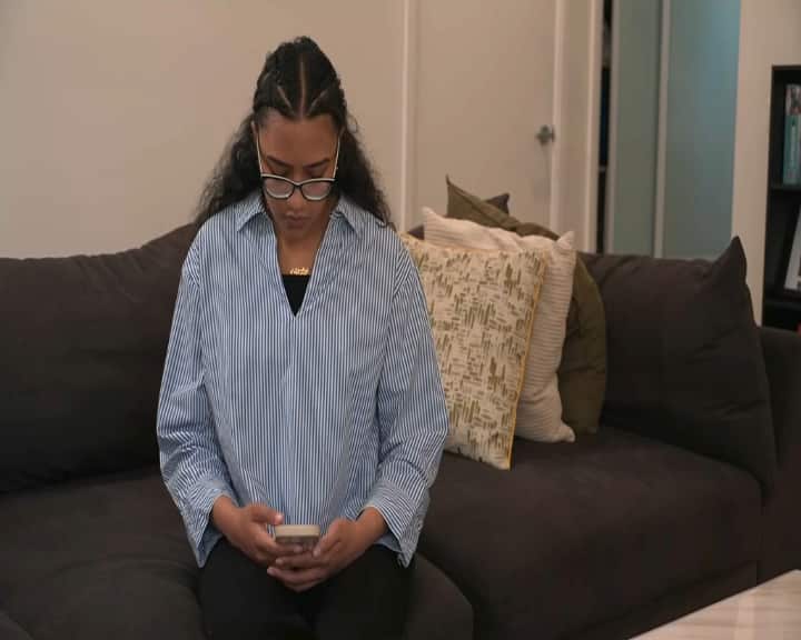 'Bayar uang tebusan': Abdullah menjawab telepon sepupunya – dan malah menemukan orang-orang bersenjata 1 Seorang wanita berkemeja bergaris sedang menatap layar ponselnya.