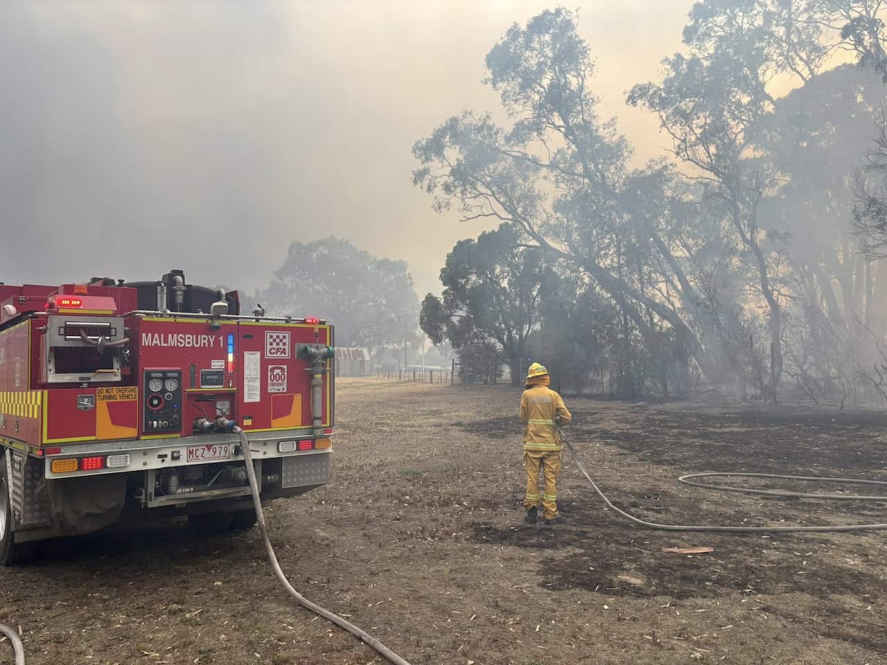 A firefighter dousing a bushfire with a hose