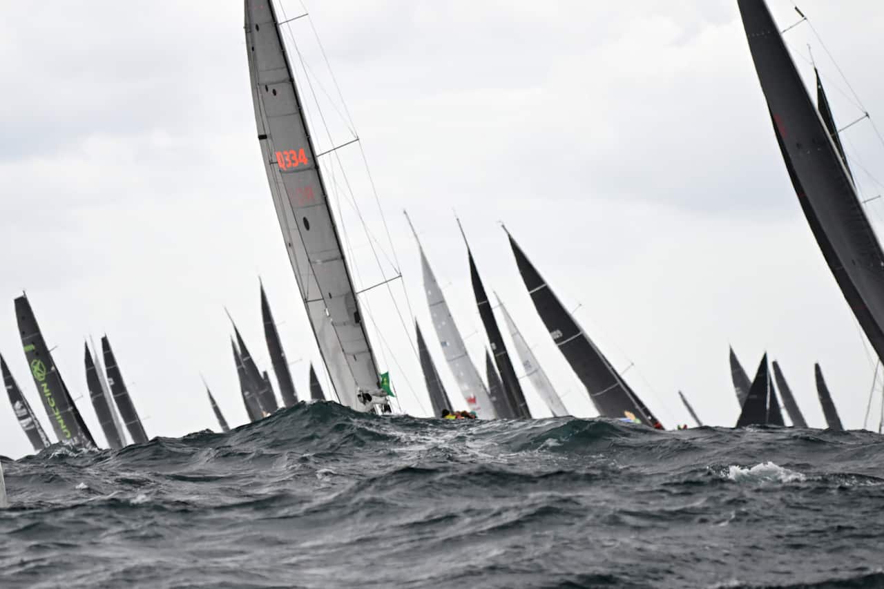 The sails of boats visible above choppy, dark seas.