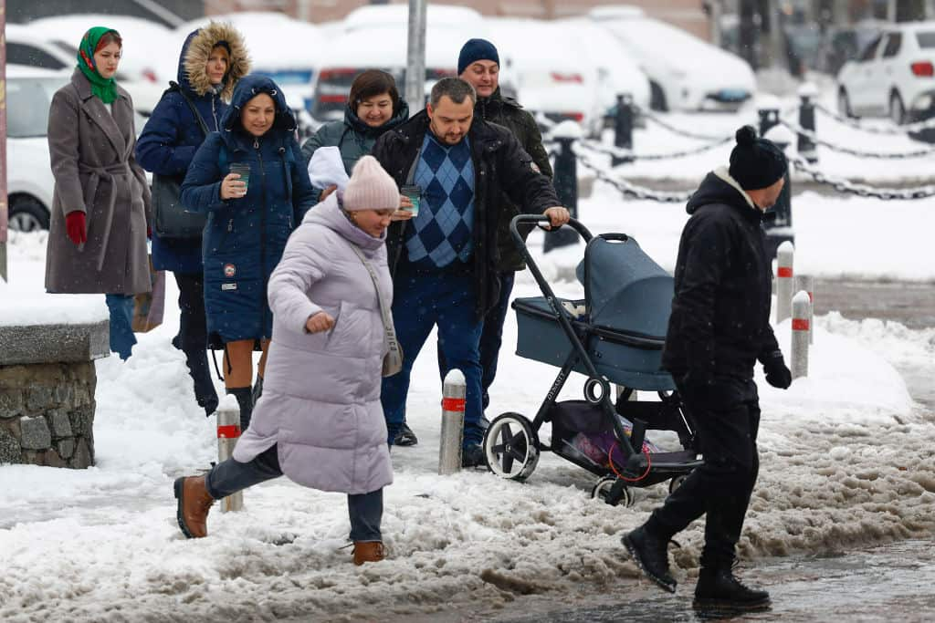 People cross a snow covered road on November 19, 2022 in Kyiv, Ukraine.