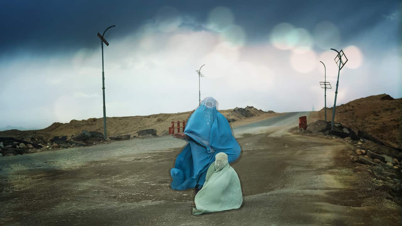 Women on a highway wearing the blue Afghan burqa called the chador.  