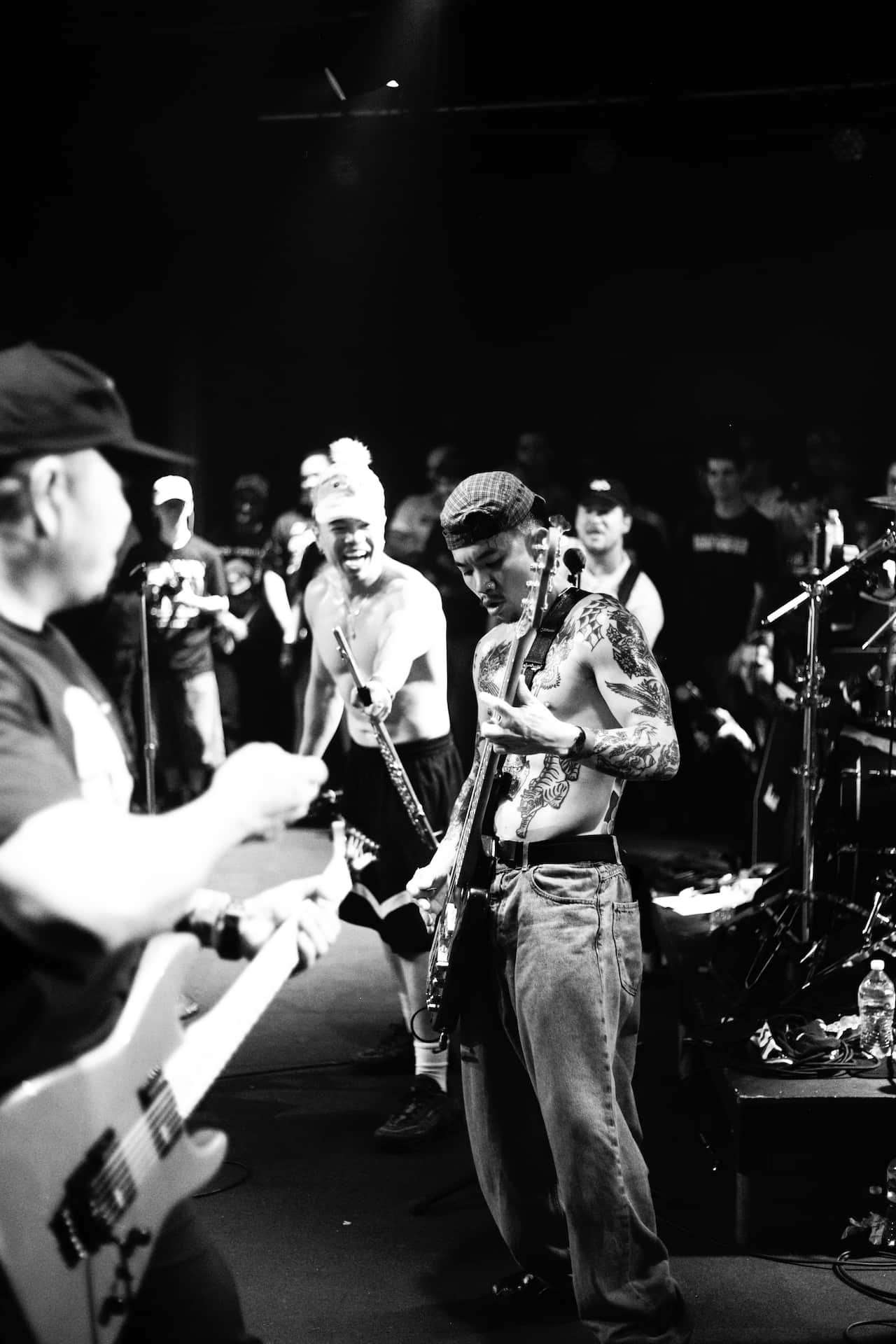 A group of people playing music on a stage with their shirts off.
