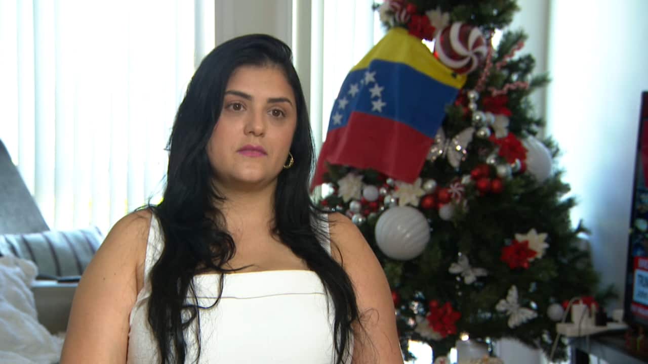 A woman in a white dress sitting next to a Christmas tree.
