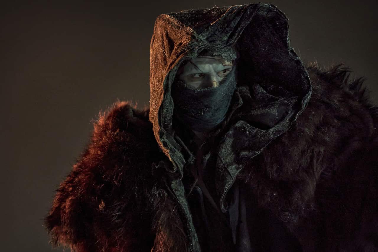 A man dressed up as a monster covered in a fur blanket