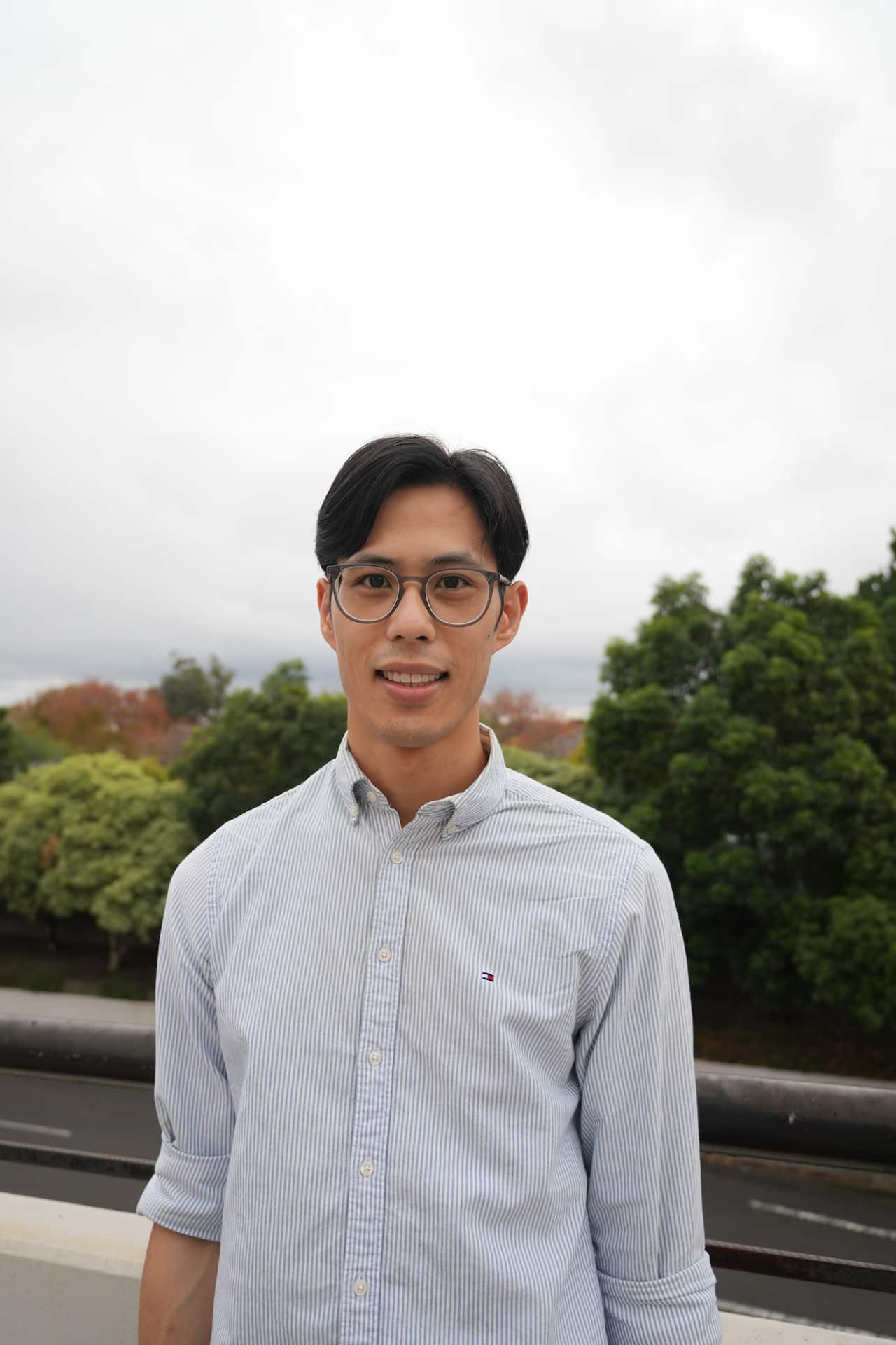 A man in a white shirt is posing for a photo outdoors.