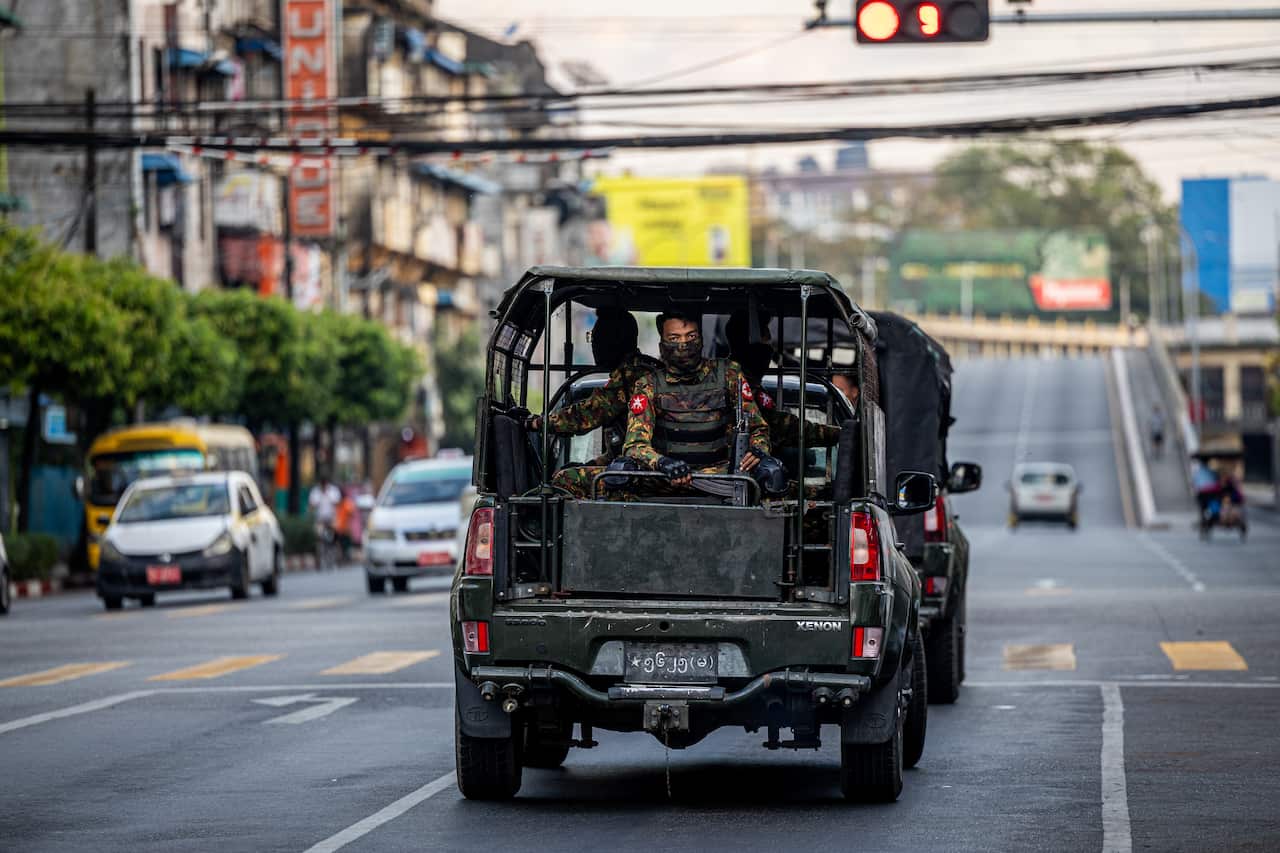 A military carring soliders driving on a city street.