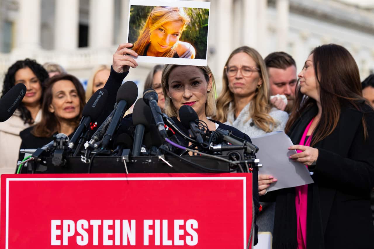Woman holds image of herself while speaking at podium